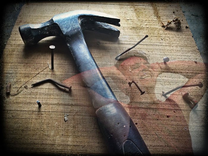 Hammer on a wood table with lots of bent nails overlay of a frustrated man